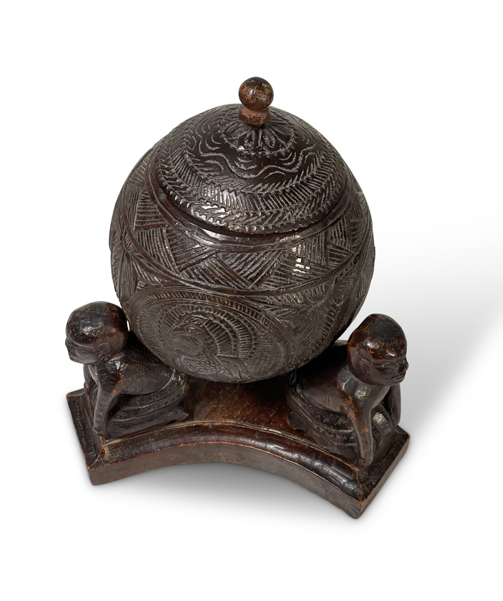 Carved Coconut with Lid Supported on a Stand fitted with Three Carved Kneeling Tribal Figures